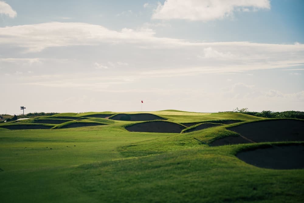 Sunlit fairway winding between bunkers towards the flag